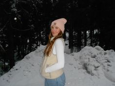 a woman standing in the snow wearing a pink hat