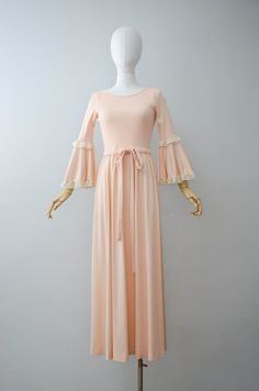 A peach maxi dress with a stretchy ribbed bodice. The half sleeves and skirt are done in a silky polyester with the bell sleeves being trimmed in lace. A drawstring tie is found at the waist and it has a back zip closure. ☛ m e a s u r e m e n t s ☚ Bust: 32-36 Waist: 27-34 Hips: open Shoulders: 11.5-14 Length: 55 ☛ d e t a i l s ☚ Era: 1970s Material: polyester Condition: excellent ☛ v i s i t t h e s h o p ☚ https://etsy.me/2Nd23kg ☛ instagram ┇ poppycockvintage ☛ facebook ┇ poppycockvintage Peach Maxi Dress, 1930s Fashion Dresses, Peach Maxi Dresses, Dress Bell Sleeve, Winston Salem Nc, Black Linen Dress, Navy Floral Dress, Winston Salem, Corduroy Dress