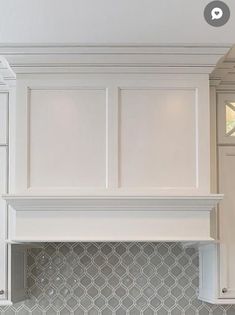 a kitchen with white cabinets and gray backsplash