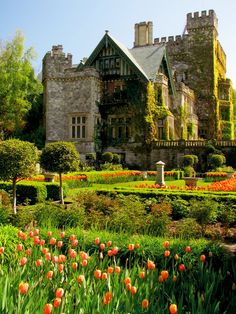 an old castle with lots of flowers in the front yard