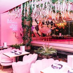 the interior of a restaurant with pink lighting and flamingos hanging from the ceiling above