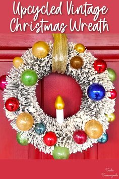 an upcycled vintage christmas wreath with colorful ornaments and a lit candle on the front door