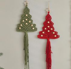 two crocheted christmas trees hanging from hooks on a wall next to each other