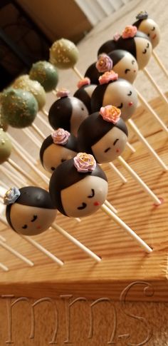 cake pops decorated with faces and flowers on sticks