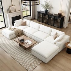 a large white sectional couch sitting in a living room next to a table and fireplace