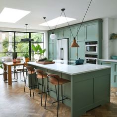 a kitchen with green cabinets and an island in front of a window that looks out onto the backyard