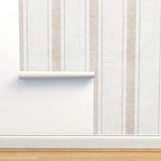 a white shelf sitting on top of a wooden floor next to a wall with vertical stripes