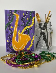 a glass jar filled with beads next to a painting and some other crafting supplies