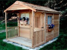 a small wooden shed sitting on top of a lush green field