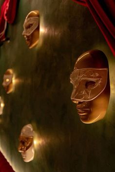 gold masks are on display in front of red velvet drapes and wall - to - wall curtains