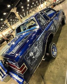 a blue car with skulls painted on it's side in a showroom next to other cars