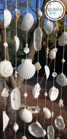 shells and seashells are hanging from a string in front of a tree with the words golanta on it