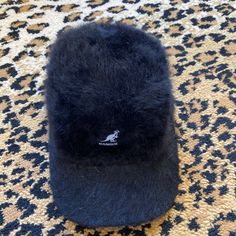 a black hat sitting on top of a carpet next to an animal print floor mat