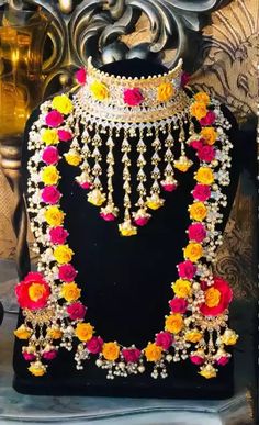 an elaborate necklace with flowers and pearls on display in front of a black velvet stand