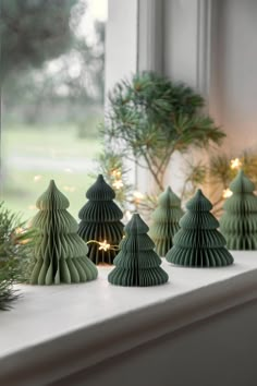 small christmas trees are sitting on a window sill