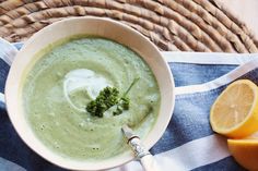 a bowl of broccoli soup with sour cream in it and an orange slice next to it