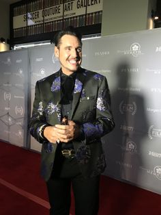 a man in a suit standing on a red carpet