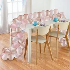 a white table with gold and white balloons in the shape of a circle on it