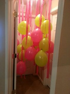 balloons hanging from the ceiling in front of a door with pink and yellow streamers