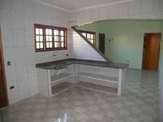 an empty kitchen with tile flooring and counter tops in the center of the room