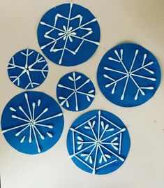 four snowflakes are shown on the wall in blue and white paper cutouts