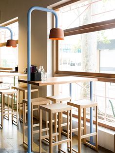 an empty restaurant with wooden tables and stools in front of a large open window