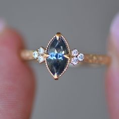 a close up of a person holding a ring with a blue and white diamond in it