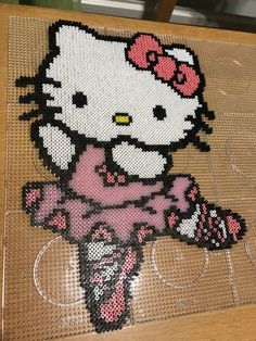 an image of a hello kitty made out of perler beads on a wooden table