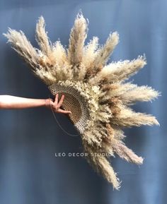 a person is holding up a fan made out of dried grass