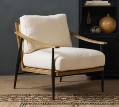 a chair sitting on top of a rug next to a book shelf and vases