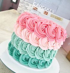 there is a large cake with pink and blue frosting on the top of it