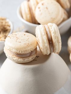 two macaroons are sitting on top of a tea pot with other macaroons in the background