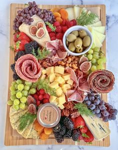 a wooden platter filled with cheese, fruit and meats