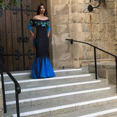 a woman in a long dress standing on the steps next to a door and stairs