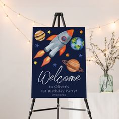 an easel with a sign that says welcome to the first birthday party on it