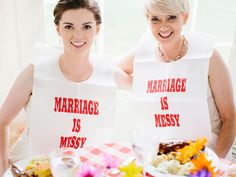 two women in white vests sitting at a table with food