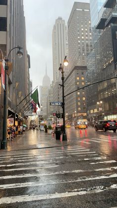 a city street with cars and people walking on it in the rain at night time