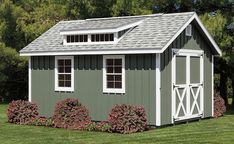 a small gray and white shed sitting on top of a lush green field