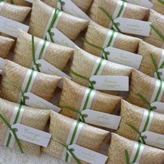 many small packages with green ribbons tied to them are sitting on a white tablecloth