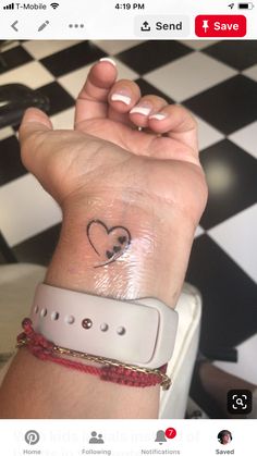 a woman's wrist with a small heart tattoo on it