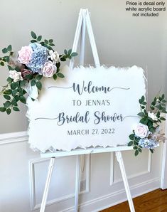 a welcome sign with flowers and greenery on it