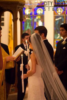 a bride and groom standing at the alter with candles in front of them, during a wedding ceremony