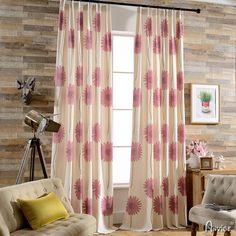 a living room with a couch, chair and window covered in pink flowered curtains