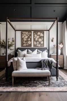 a canopy bed in a bedroom with white and gray decor on the walls, along with two paintings above it