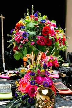 a vase filled with lots of colorful flowers on top of a black cloth covered table