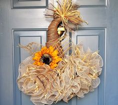 a sunflower and burlock wreath is hanging on a blue front door with a yellow flower