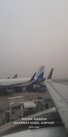 two airplanes are parked on the tarmac at an airport, with other planes in the background