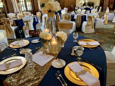 the tables are set with gold and blue linens, white flowers, and candles