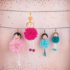 three little dolls hanging on a line with clothes pins in the shape of balls and flowers