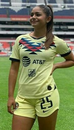 a female soccer player is posing for a photo on the field with her hands in her pockets